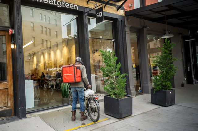 A Doordash delivery man with bicycle outside a sweetgrene